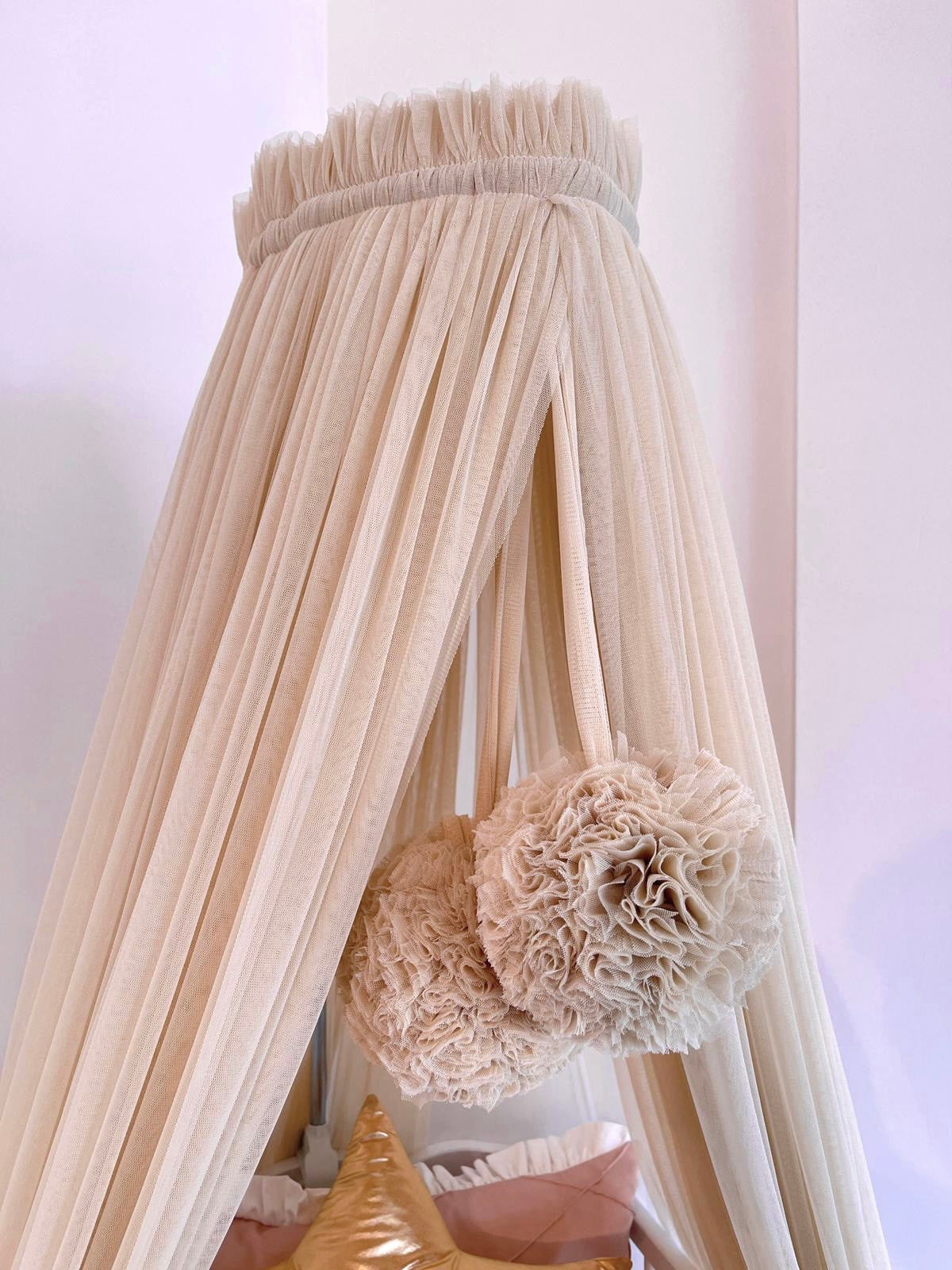 Beige bed canopy with pompoms