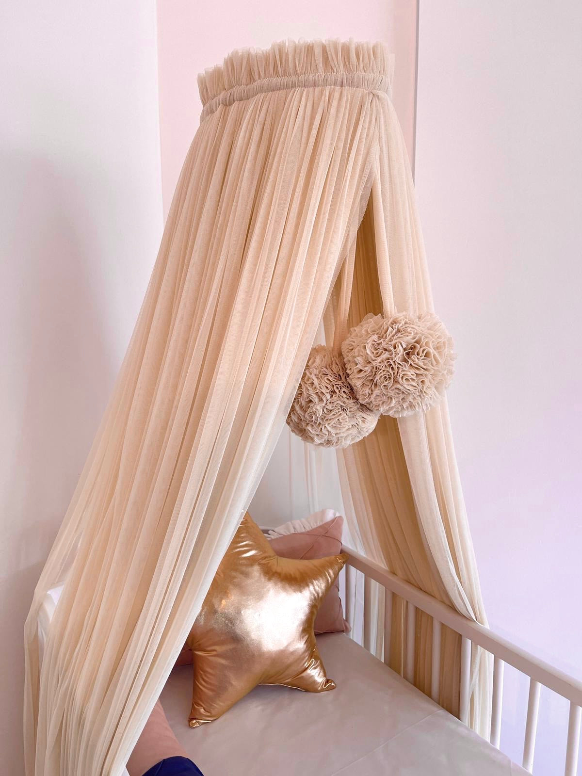 Beige bed canopy with pompoms