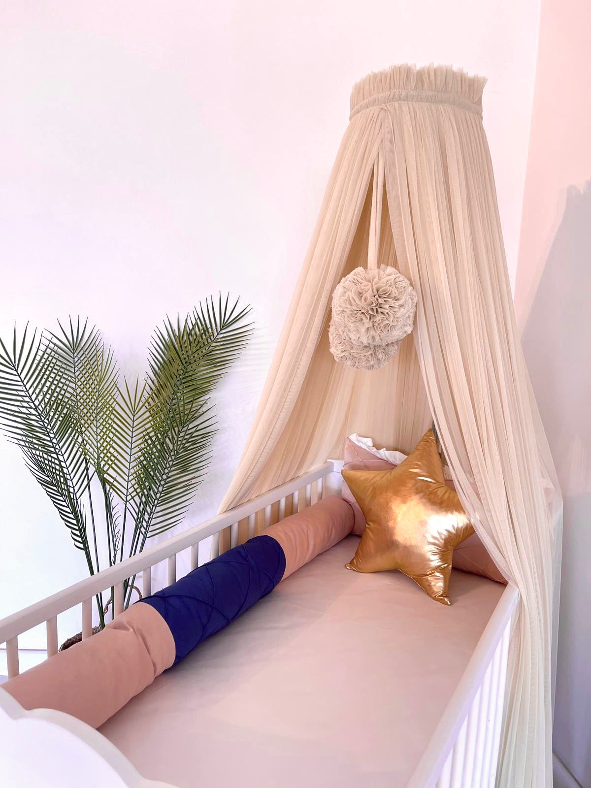Beige bed canopy with pompoms