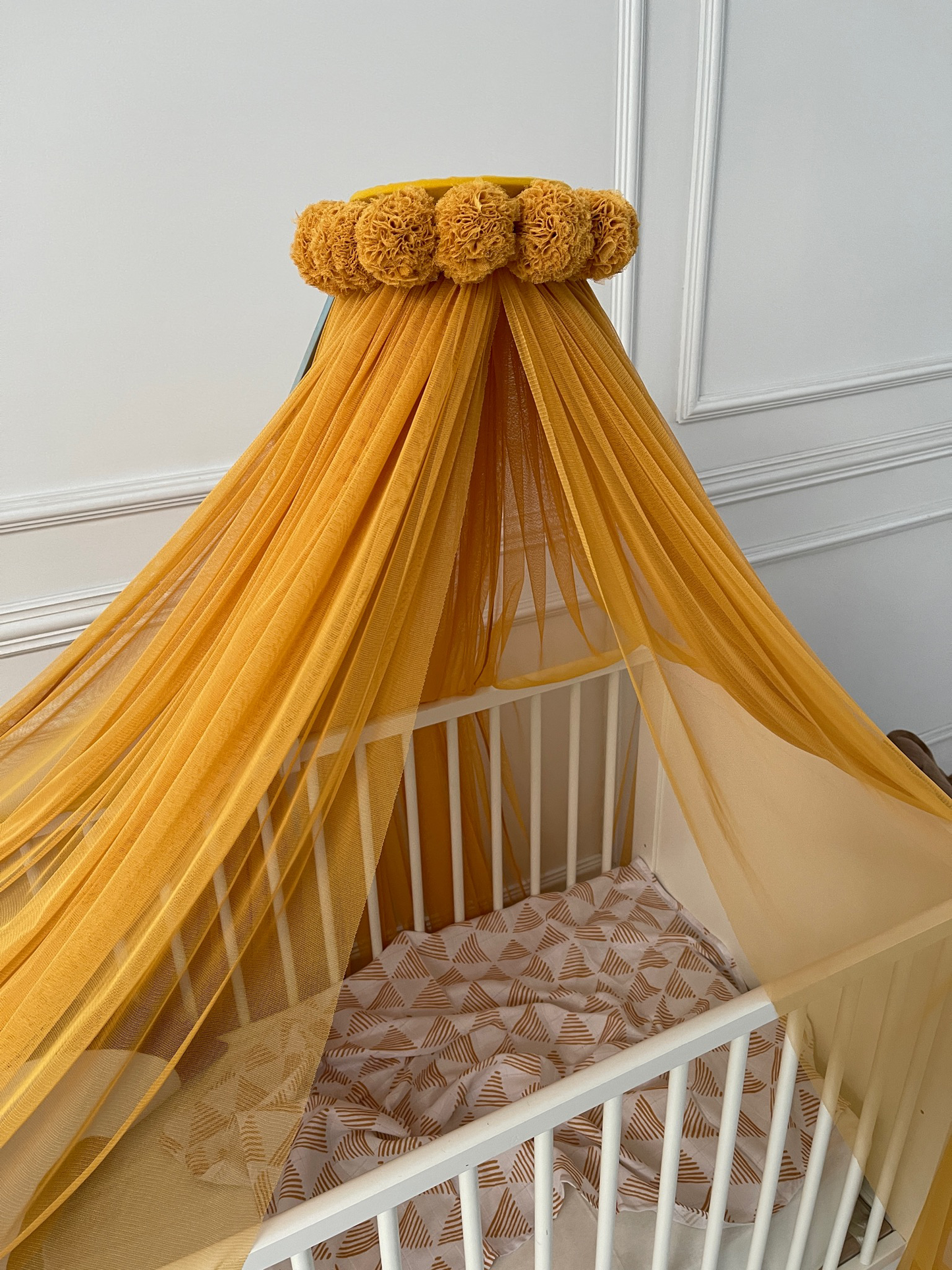 Mustard yellow bed canopy with pompom wreath