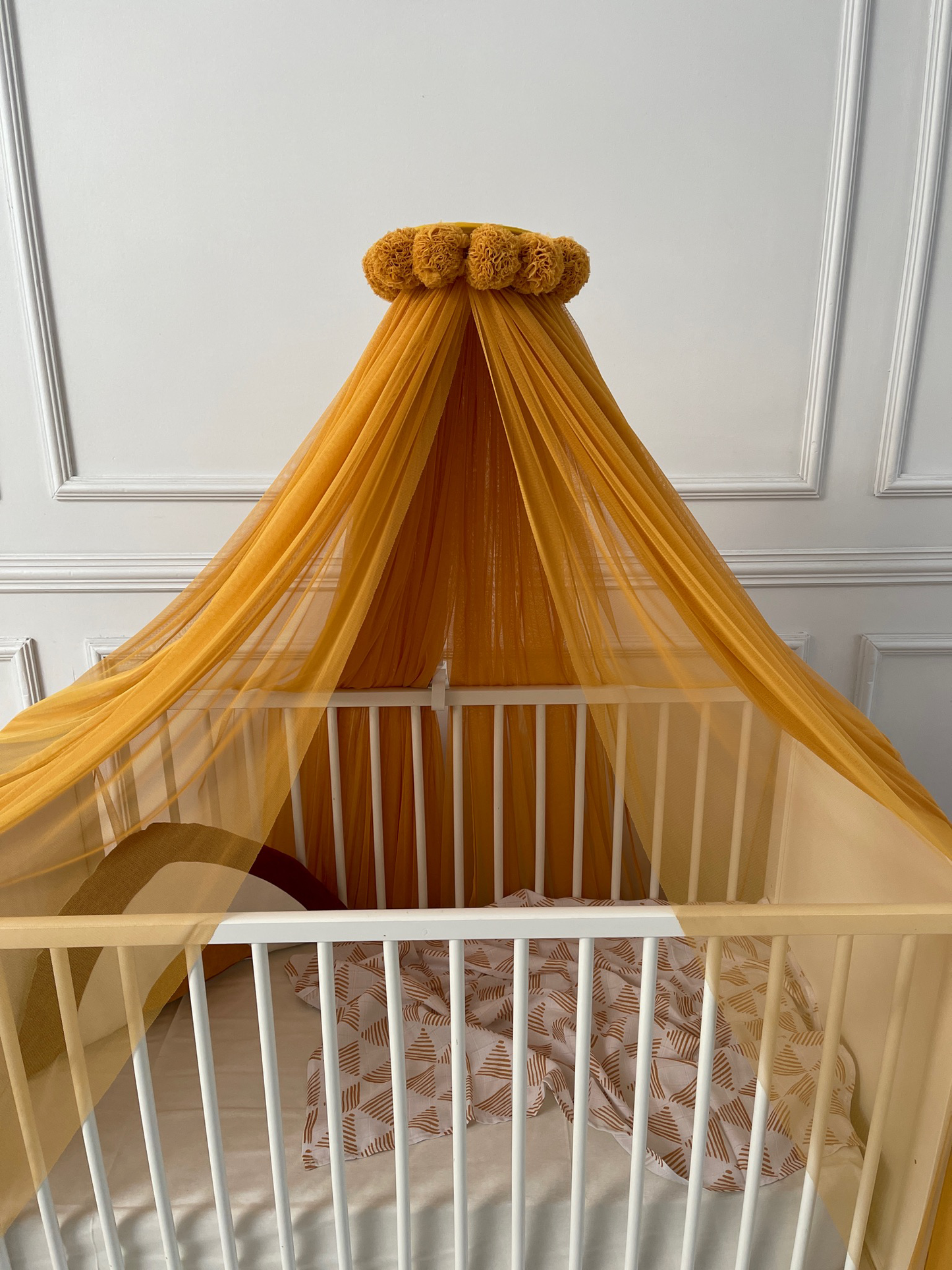 Mustard yellow bed canopy with pompom wreath