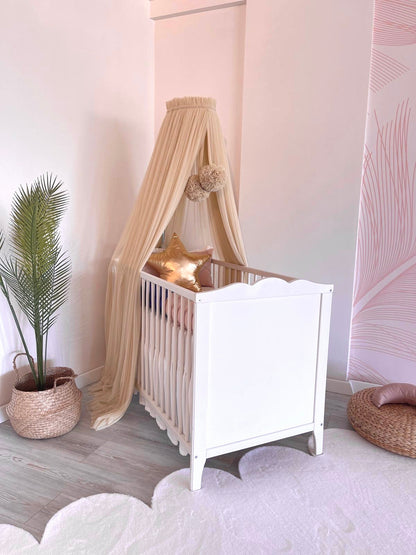 Beige bed canopy with pompoms