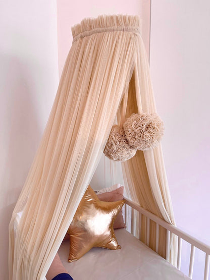 Beige bed canopy with pompoms