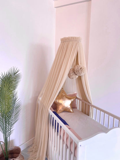 Beige bed canopy with pompoms